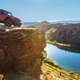 A red Jeep Gladiator pickup parked on a cliff